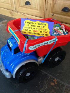 a blue and red toy truck filled with lots of stuff on top of a kitchen floor