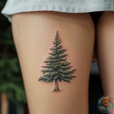 a woman's thigh with a small pine tree tattoo on the side of her leg