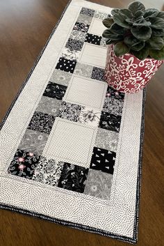 a potted plant sitting on top of a table next to a black and white quilt