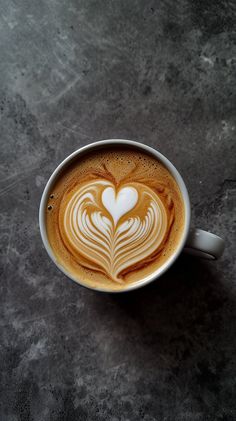 a cappuccino in a white cup with hearts on it's foam