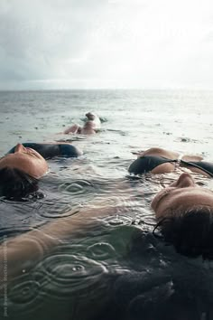 several people are swimming in the ocean with their backs turned to the camera and one person is laying on his stomach