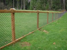 a wooden fence with green grass and trees in the background