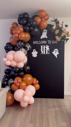 some balloons that are in the shape of ghost and welcome to me sign on a wall