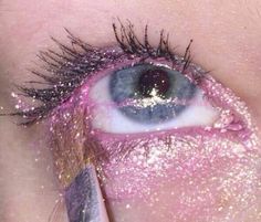 an eye with glitter on it and a pencil in the iris's left eye