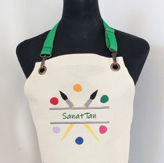 a white apron with green straps on top of a mannequin's head