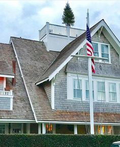 an american flag is flying in front of a house with a car parked on the street