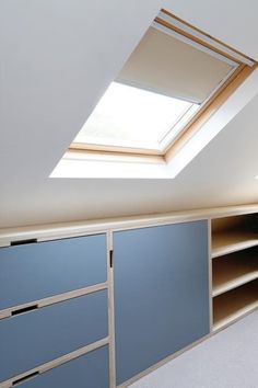 an attic bedroom with skylight and built - in shelving units, carpeted flooring