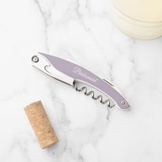 a bottle opener sitting on top of a marble counter next to a corkscrew