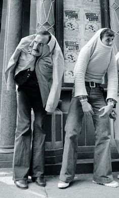 three men standing on the sidewalk with their hands in their pockets