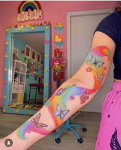 a woman with colorful tattoos on her arm and leg is standing in front of a mirror