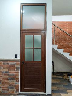 a cat sitting on the floor in front of a door with glass and wood paneling