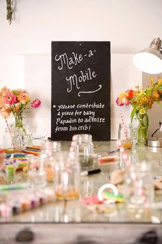 a table topped with lots of vases filled with flowers next to a chalkboard