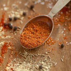 a spoon filled with spices on top of a wooden table