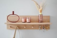 a wooden shelf with two glasses, a vase and keys on it next to a handbag