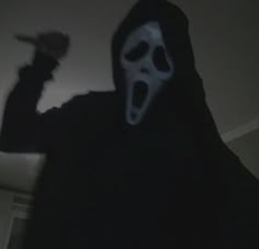 a person wearing a ghost mask and holding a hat