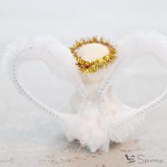 a white and gold ring with feathers on it's sides, sitting in the sand