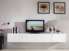 a flat screen tv sitting on top of a white entertainment center next to vases