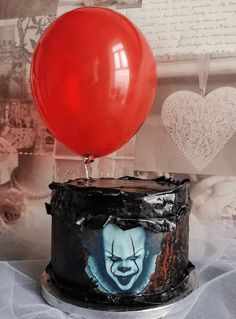 a birthday cake with a clown face on it and a red balloon attached to the top