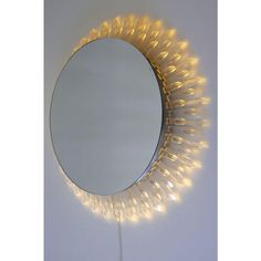 a round mirror with lights around it on a white wall next to a light stick