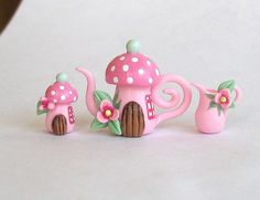 three pink teapots with flowers and mushrooms on them