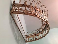 a mirror hanging from the side of a wall with a crown on top of it