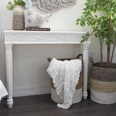 there is a white table with some plants on it and two baskets next to it