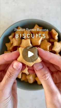 two hands holding a peanut butter banana biscuit in front of a bowl of peanuts