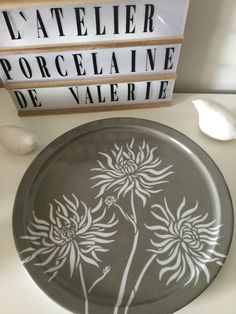 a black and white plate sitting on top of a table next to a sign that says atelleier porcelaine de vale