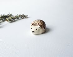 a small hedgehog figurine sitting next to a flower on a white surface