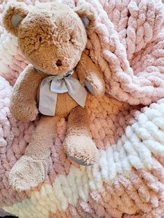 a teddy bear sitting on top of a blanket