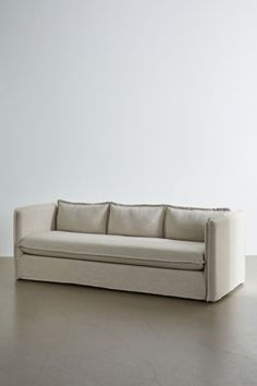 a white couch sitting on top of a hard wood floor next to a white wall