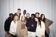 a group of people standing next to each other in front of a white curtained wall