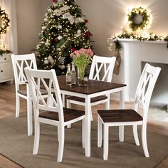 a dining room table and chairs in front of a christmas tree