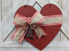 a red heart hanging on a wooden wall with a ribbon tied around it and a tag in the middle