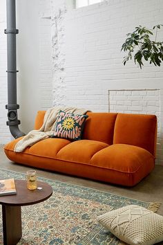 an orange couch sitting on top of a rug in a living room