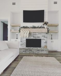 a living room with a white couch, fireplace and flat screen tv on the wall