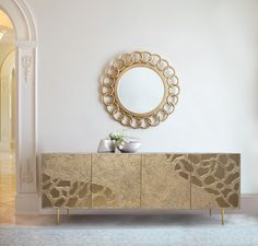 a large mirror sitting on top of a wooden cabinet next to a vase and potted plant