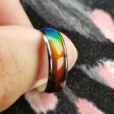 a person wearing a ring with a colorful design on it's side and their finger in the foreground