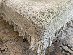 a bed with a blue and white bedspread sitting on top of a rug