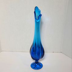 a blue glass vase sitting on top of a white table