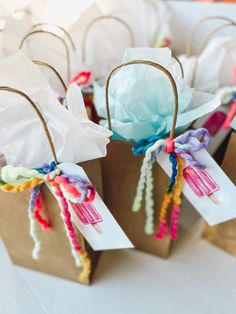 small paper bags with colorful ribbons tied to them on a white tablecloth covered table