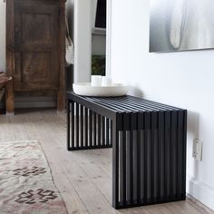 a wooden table sitting on top of a hard wood floor next to a white wall