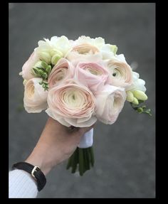 a person holding a bouquet of white and pink flowers in their hand on the street