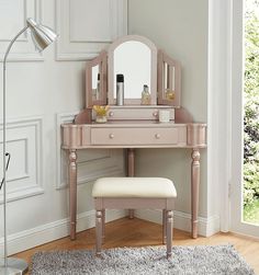 a pink dressing table with mirror and stool