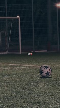 a soccer ball sitting on top of a field next to a goalie's net