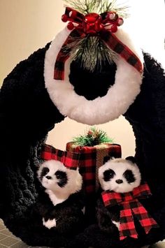 two stuffed panda bears are sitting in front of a christmas wreath with a bow on it