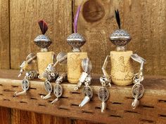 four bottles with charms sitting on top of a wooden shelf