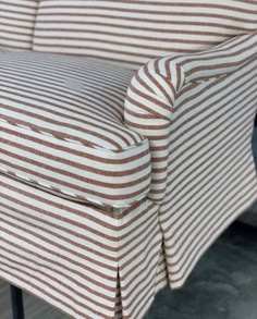 the back of a chair with brown and white stripped fabric on it's arm