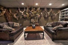 a living room with couches and deer heads on the wall