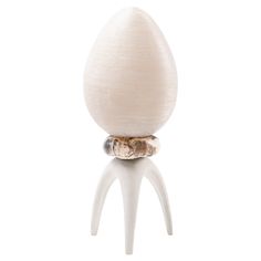 an egg sitting on top of a white stand with two rings around it's legs